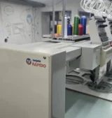 ordado industrial Camisetas Rápido Máquina de bordar industrial Tajima com a marca Camisetas Rápido na fábrica de São Paulo.