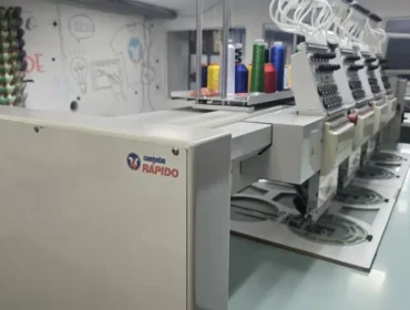 Máquina de bordar industrial Tajima com a marca Camisetas Rápido na fábrica de São Paulo.